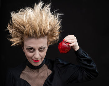 Portrait of young woman against black background