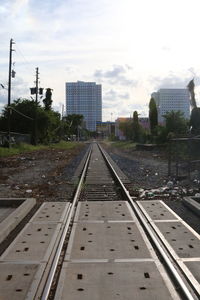 Railroad tracks in city against sky