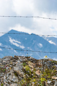 Barbed wire separating the mountain landscape. in the foreground there are solid stones and mountain