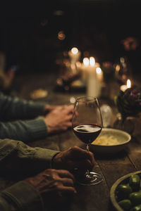 Hand of senior man holding wineglass at dining table during party