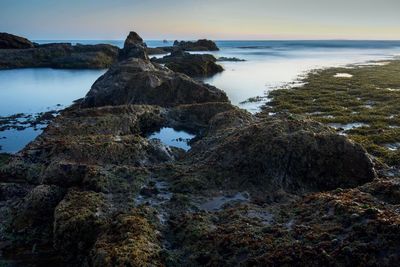 Rock formation in sea against sky