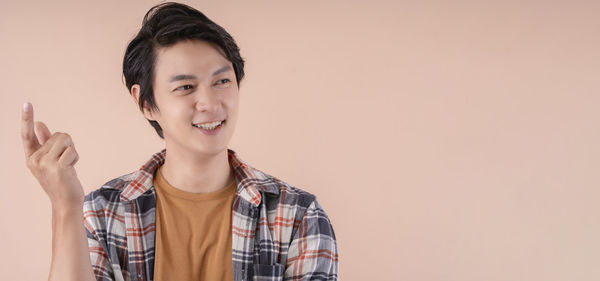 Portrait of smiling young man against gray background