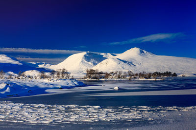 Scenic view of snowcapped mountains against blue sky