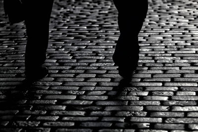 Low section of woman walking on cobblestone street