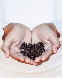 Close-up of woman hands holding roasted coffee beans