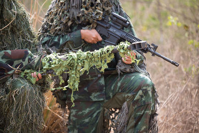 Army soldiers with rifle kneeling in forest
