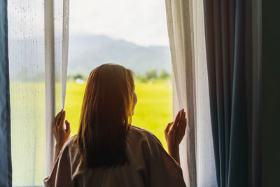 Rear view of woman looking through window