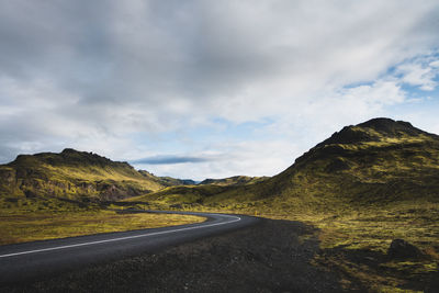 Empty road by mountains against sky