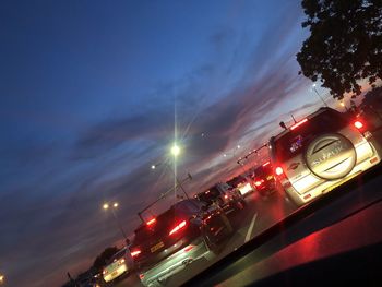 Cars on illuminated road against sky at night