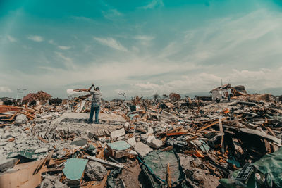 Rear view of man standing at abandoned buildings against sky