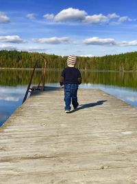 Rear view of man on lake against sky