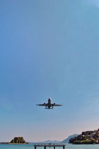 Low angle view of airplane flying in clear blue sky