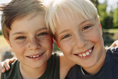 Portrait of happy boy with blond male friend at summer camp