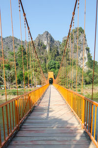 Footbridge by mountain against clear sky