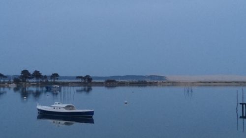 Sailboats moored in lake against clear sky