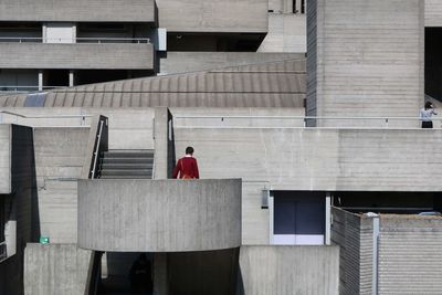 Rear view of man standing on staircase against building