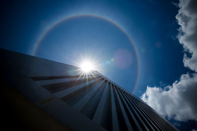 Low angle view of rainbow against blue sky on sunny day