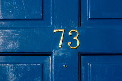 House number 73 on a blue wooden front door in london 