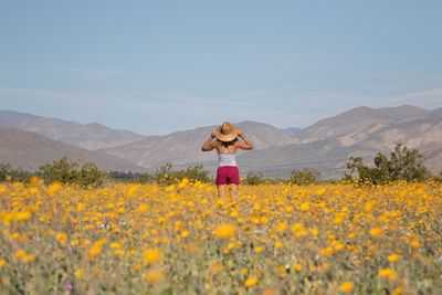 Rear view of person standing on field against mountain