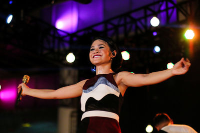 Smiling woman performing on stage at night