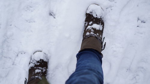 Low section of person wearing snow covered shoes