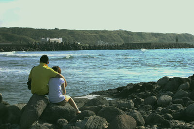 Couple sitting on rocks in front of river