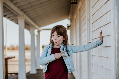 Portrait of young woman standing against wall