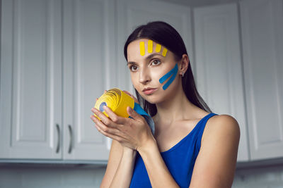 Woman holds three skeins of kinesio tape in her hand yellow and blue