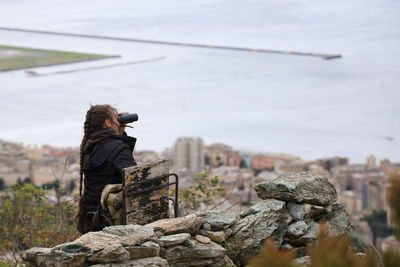 Woman looking through binoculars against sea