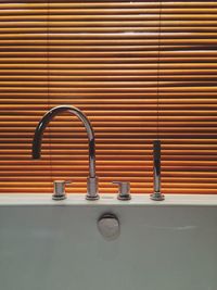 Close-up of faucets on bathtubs against window