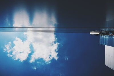 Low angle view of power lines against cloudy sky