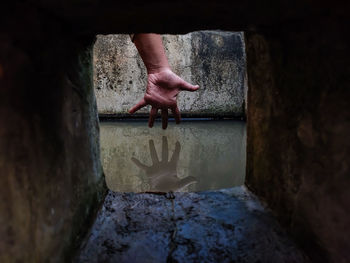 The reflection of a girl's hand fellon a water-filled cistern.