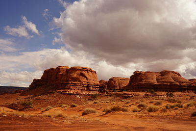 Rock formations on landscape against cloudy sky