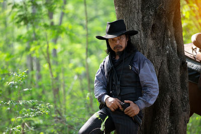 Full length of man standing by tree trunk in forest