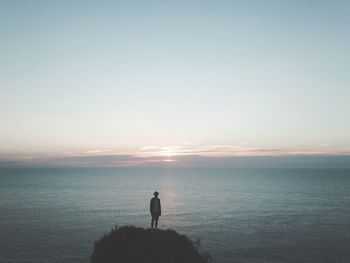 Silhouette man standing on beach against clear sky