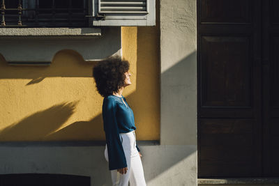 Smiling young businesswoman leaning on building