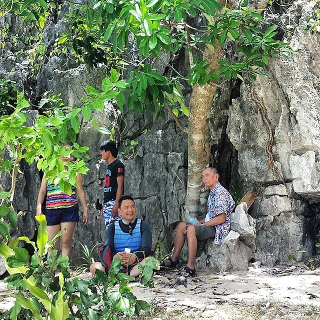 lifestyles, leisure activity, casual clothing, sitting, plant, full length, growth, young adult, person, standing, rear view, tree, men, relaxation, leaf, rock - object, nature