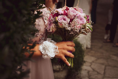 Midsection of bridesmaid holding flower bouquet