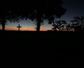 Silhouette trees on field against sky at sunset