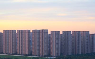 Modern buildings against sky during sunset