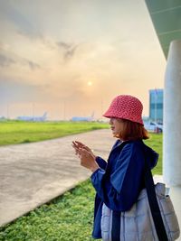 Rear view of woman standing on road against sky during sunset