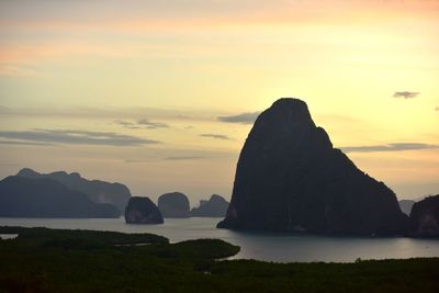 Rock formation in sea against sky during sunset