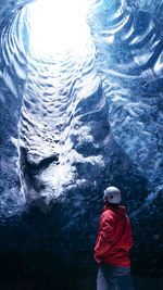 Rear view of man standing in ice cave