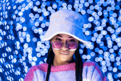 Joyful woman of color with a white beanie braided hairstyle and pink glasses enjoying the christmas 