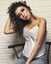 Portrait of beautiful woman sitting against wall