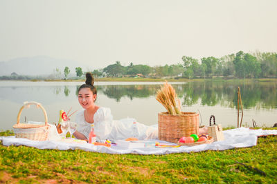 Woman smiling by lake against sky