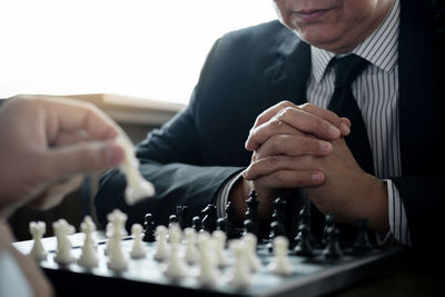 Midsection of businessmen playing chess