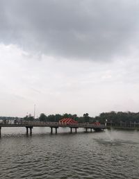 Bridge over river against sky in city