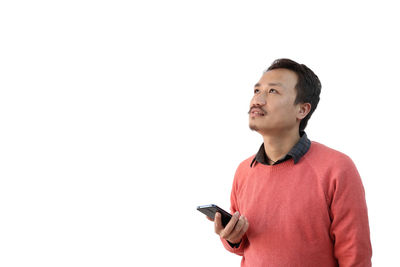 Man looking away while standing against white background