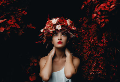 Portrait of young woman standing amidst plants at night